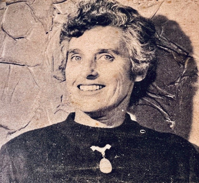 A sepia tinted photo of a woman with short grey hair smiling confidently