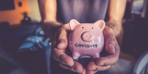 Hands holding a piggy bank with COVID-19 written on it