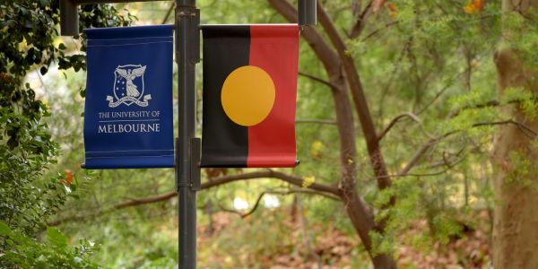 unimelb and indigenous flags in a bush setting