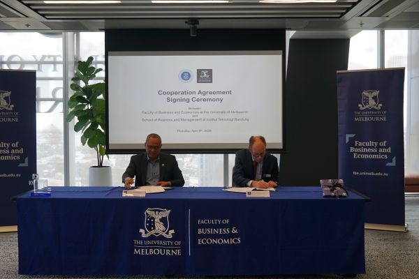 Two men signing agreement at a table 