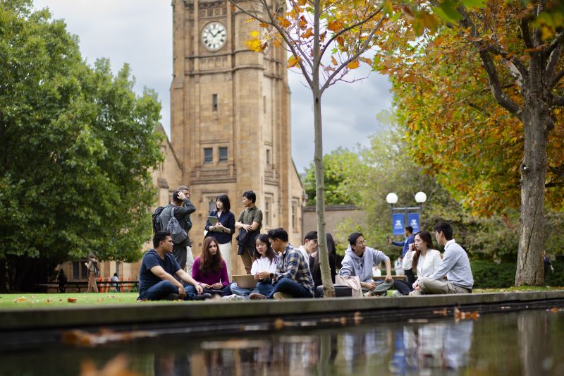 Group of students sitting outside on grass chatting