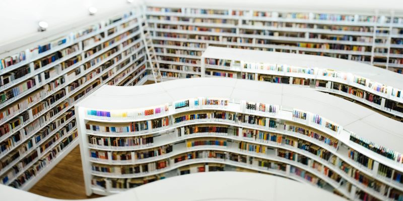 library of curved white shelving filled with colorful books