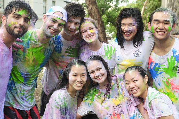 group of happy people covered in multi- coloured paint