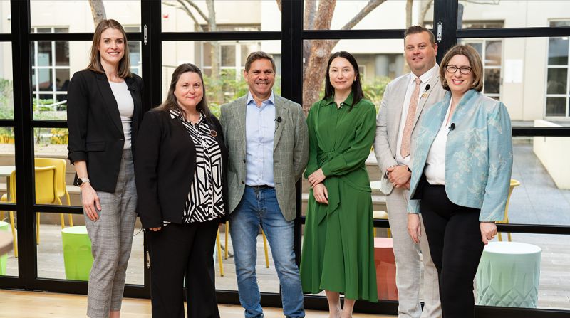 A group of six people smile and pose for a photo