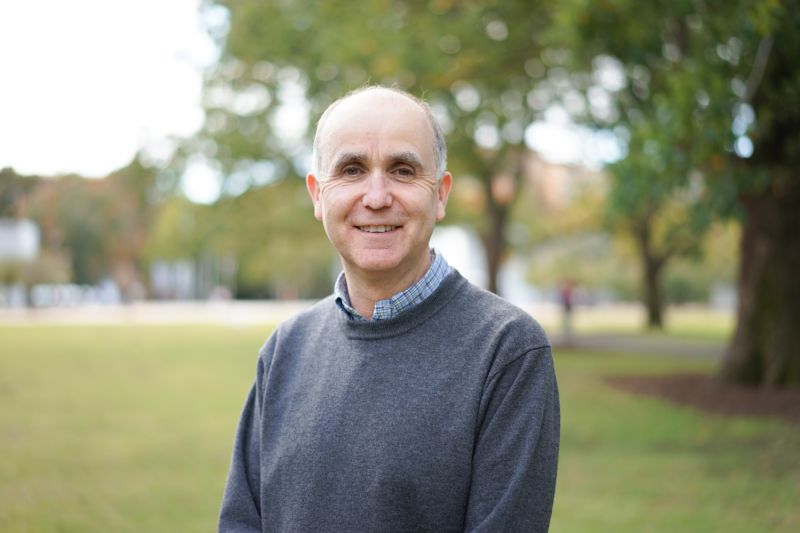 A smiling man poses for a headshot outside.