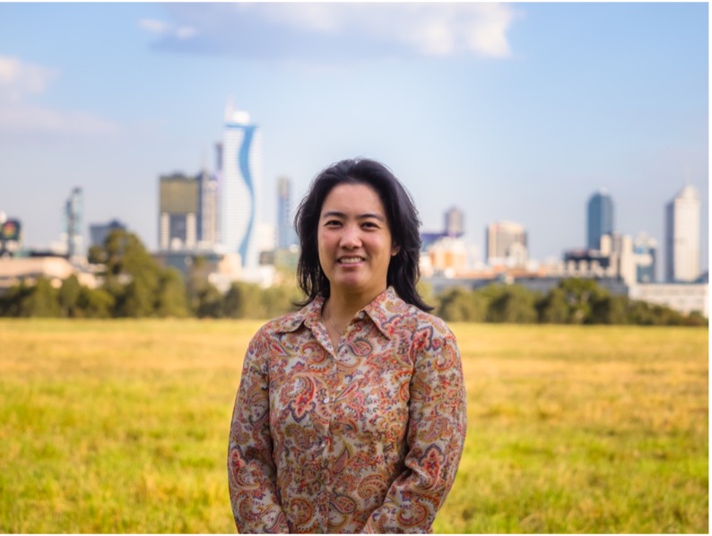 A woman stands in an open field while smiling