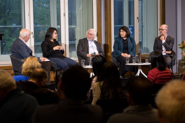 Five people having a discussion on a stage in front of an audience