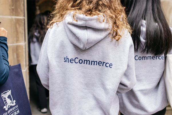 female wearing a grey hoodie with sheCommerce on the back