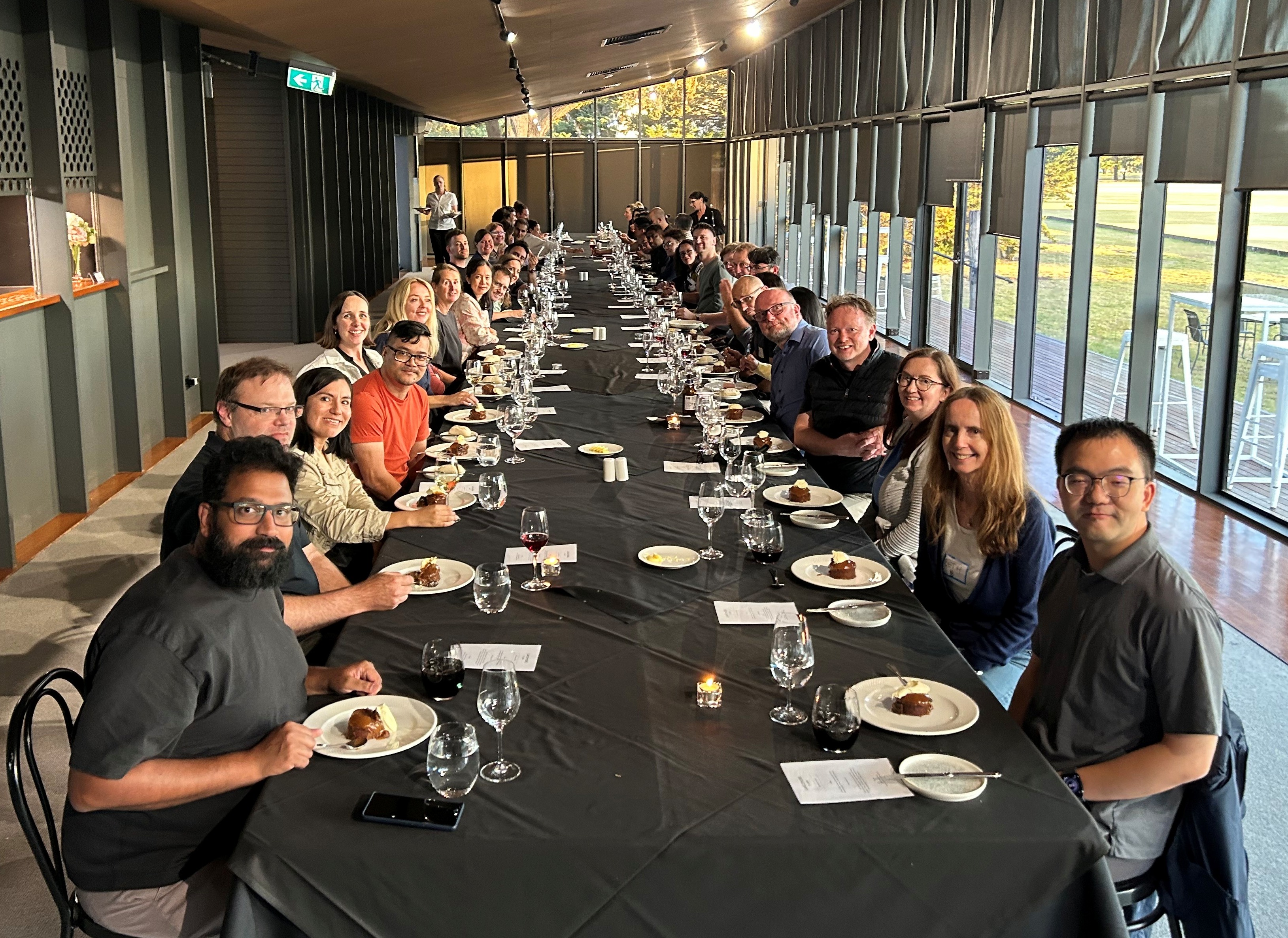 Members of the Melbourne Institute eat dessert at a long table.