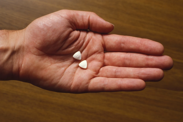hand holding two small white pills