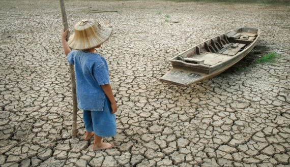 A boy looking into a boat on a dry ocean