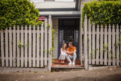 Two people sit happily on the front steps of a house.