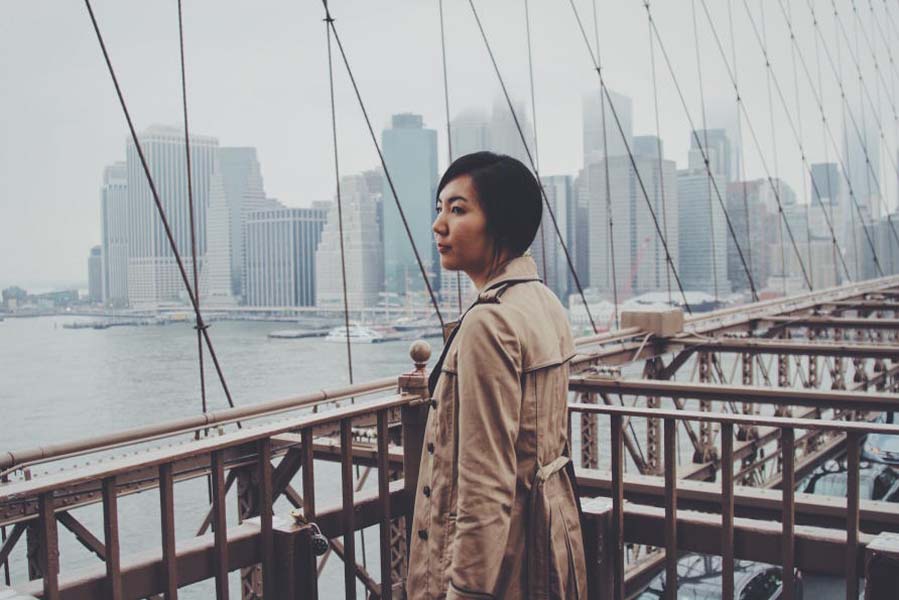 female standing on the Brooklyn Bridge looking over Manhattan